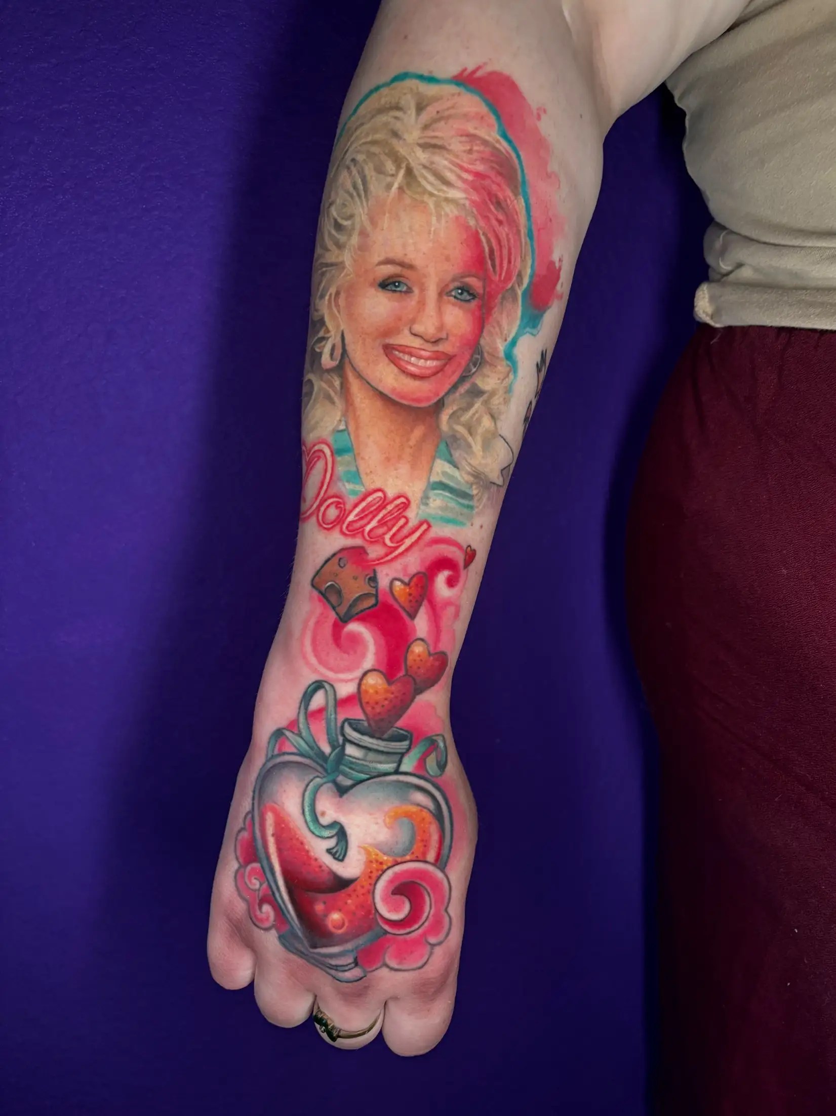 A realistic portrait tattoo of Dolly Parton with a colorful glass heart