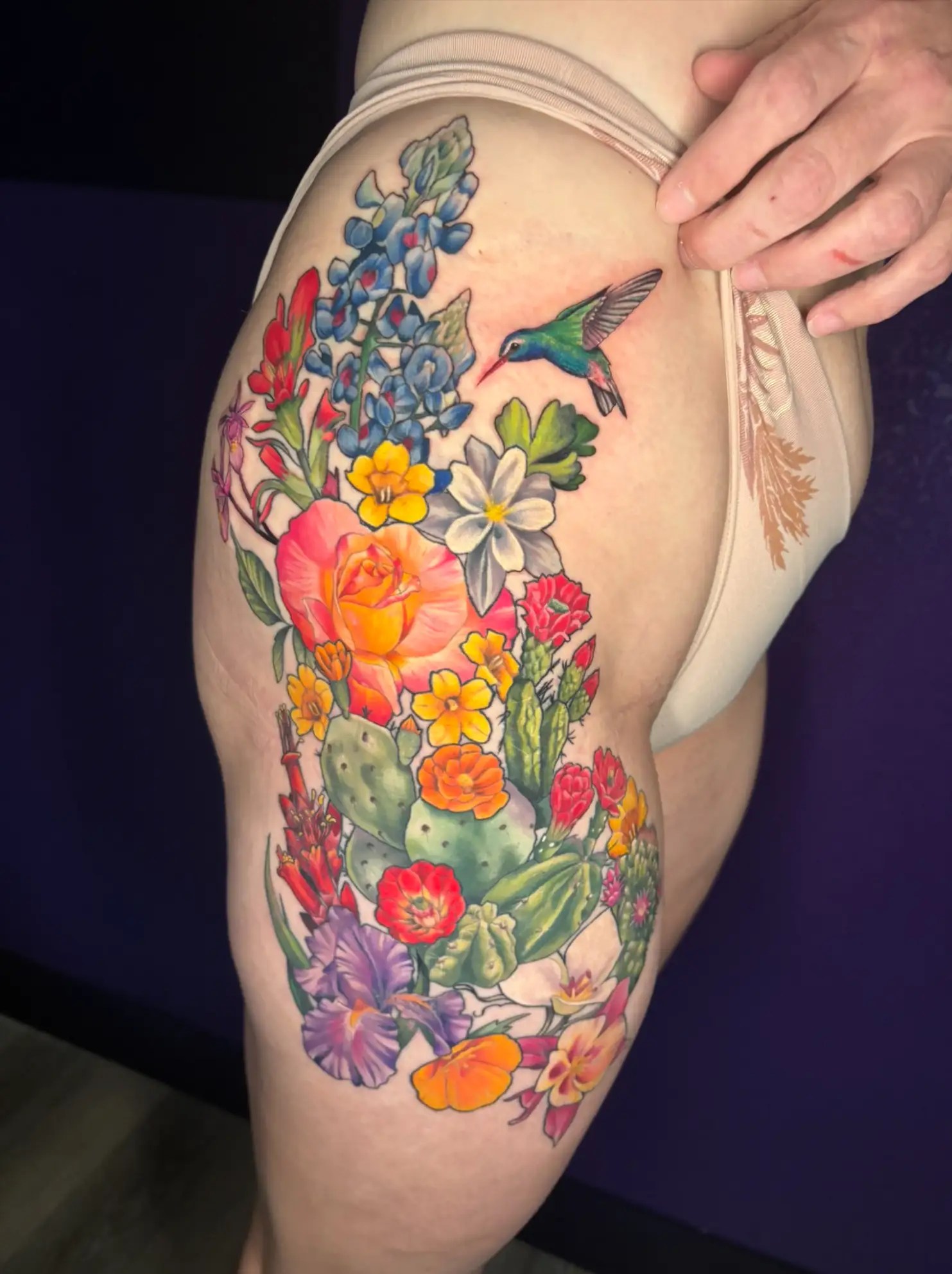 Colorful tattoo of desert flowers and cacti with a hummingbird