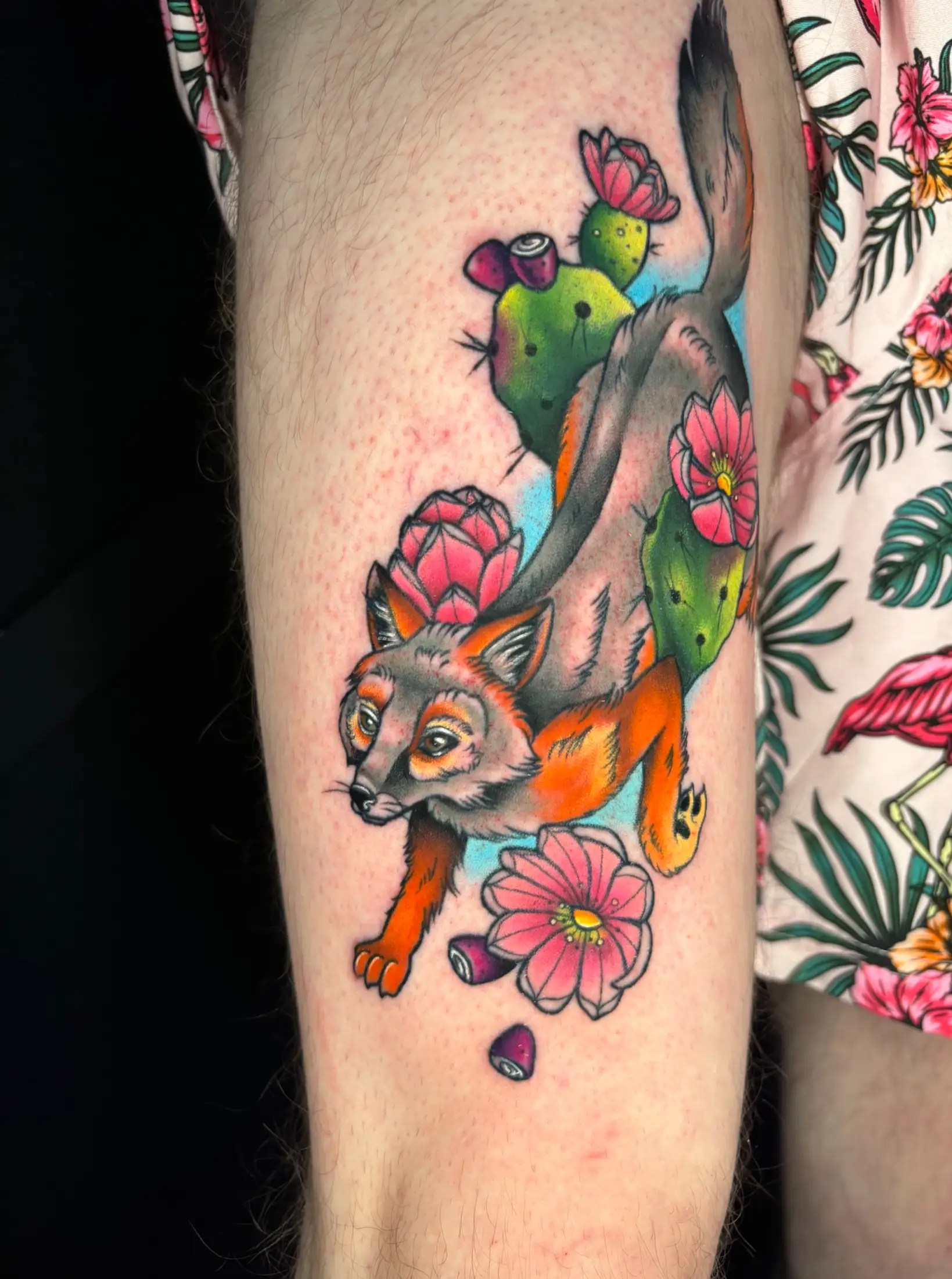 Colorful tattoo of a desert fox in the midst of a flowering cactus