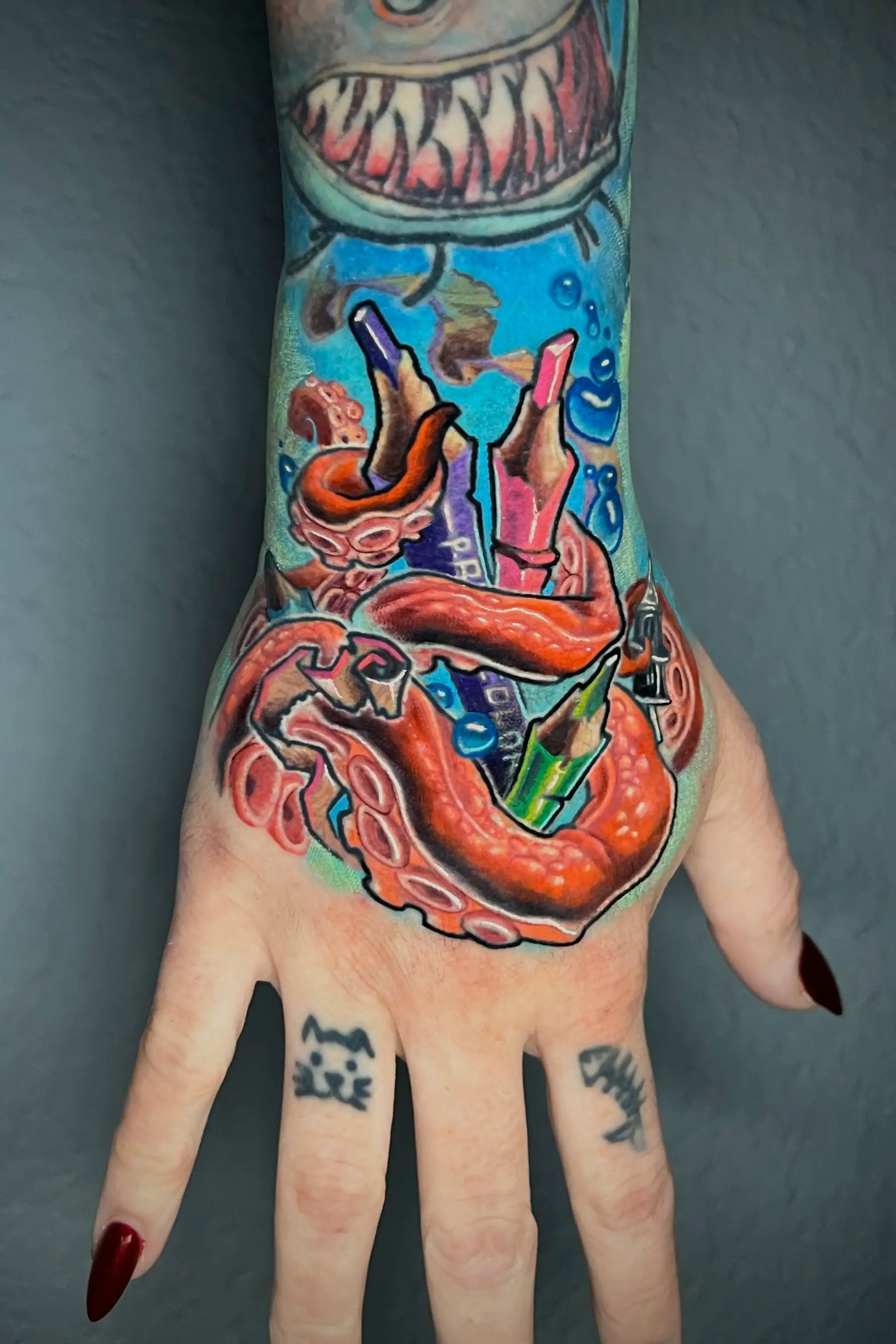 New school tattoo of a tentacle holding colored pencils and a tattoo cartridge