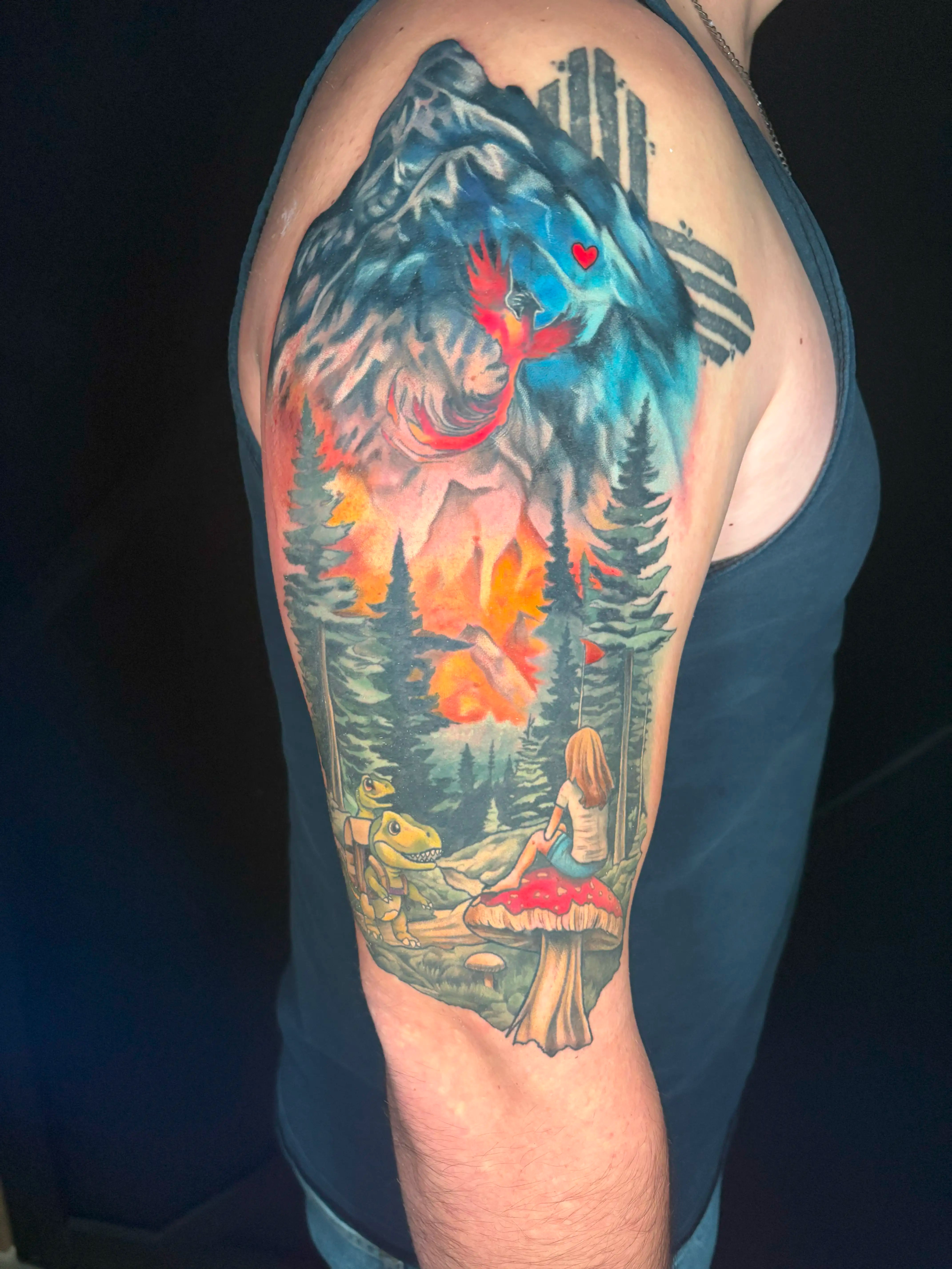 Detailed tattoo of a mountain and forest scene with an oversized mushroom, backpacking dinosaurs, and a phoenix.